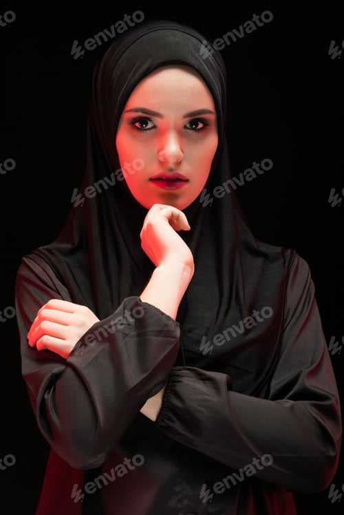 Preview: Portrait of beautiful serious young muslim woman wearing black hijab as conservative fashion concept