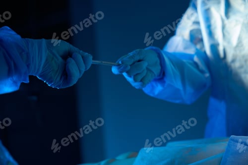 Preview: Assistant handing sterile instrument to doctor surgeon during operation