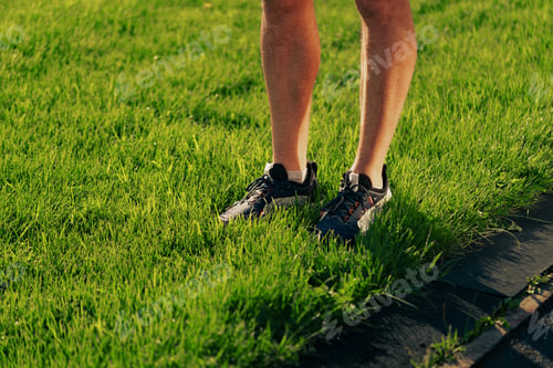 Preview: Standing on vibrant green grass with athletic shoes during daylight in a serene outdoor environment