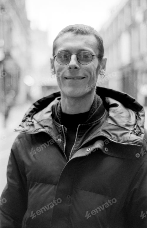 Preview: Smiling man wearing glasses and a winter coat in city street portrait