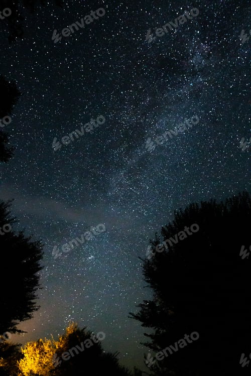 Preview: Amazing starry night sky with Milky way and stars above tourists tents in woods in mountains