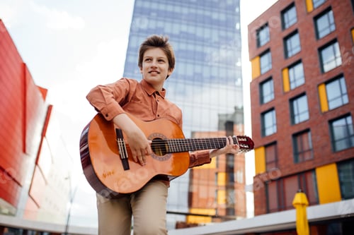 Preview: Handsome preteen plays guitar in the park, bottom view,