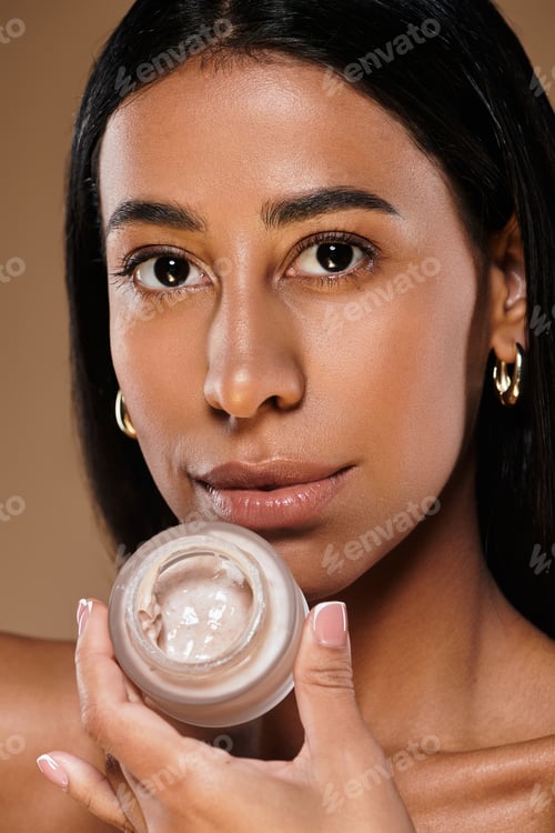 Preview: Beautiful African American woman with brunette hair showcasing skincare in studio setting