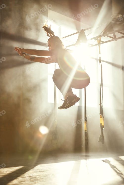 Preview: Higher and higher. Side view of young athletic woman in sport clothing jumping while exercising