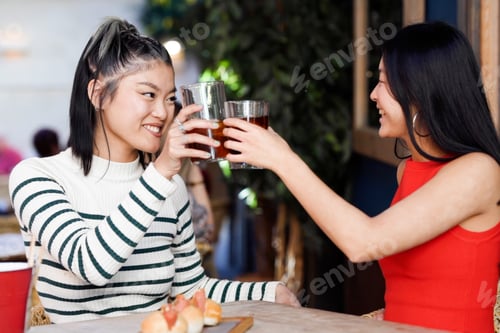 Preview: Two females in casual clothing rejoice in achievement with cheerful conversation and beverages