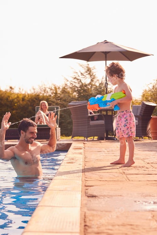 Preview: Son Squirting Father With Water Pistol Playing In Swimming Pool On Summer Vacation