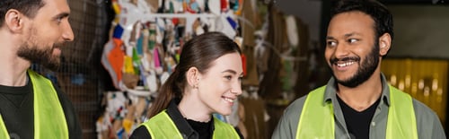 Preview: Positive young woman in high visibility vest looking away while standing and resting