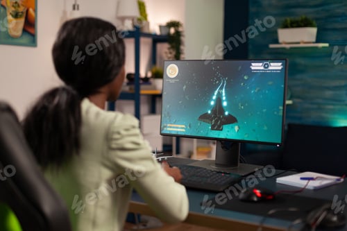 Preview: African american cyber gamer sitting at gaming desk