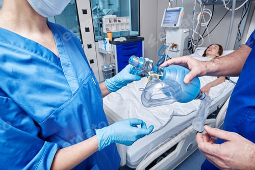Preview: Doctors holding oxygen mask over female patient's face in intensive care unit for CPR