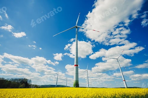 Preview: Wind turbines in a yellow field against a blue sky. Ecological energy production by windmills