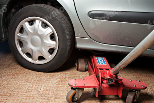 Preview: Close up of car lifted with car jack at auto mechanic workshop.
