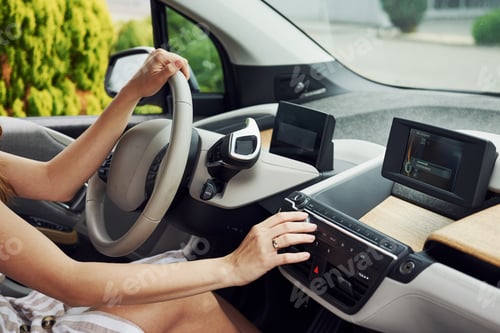 Preview: Turns the knob. Female driver inside of modern automobile. Testing brand new car