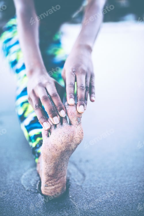 Preview: Women stretching legs before workout on the beach