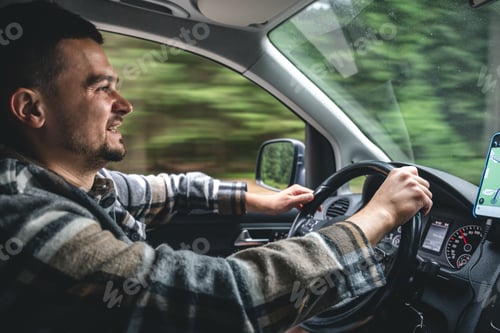 Preview: A man driving a car rides in a mountainous forest area.