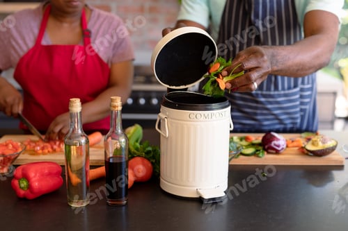 Preview: Midsection of african american senior couple cooking together in kitchen using compost bin