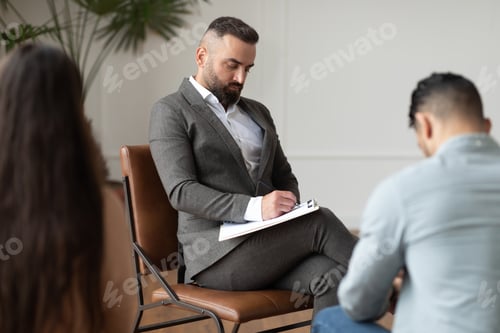 Preview: Couple sitting at therapy session with therapist, man taking notes