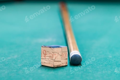 Preview: A cue stick and a chalk on a pool table