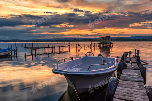 Preview: Stunning sunset at sea shore with boat at jetty