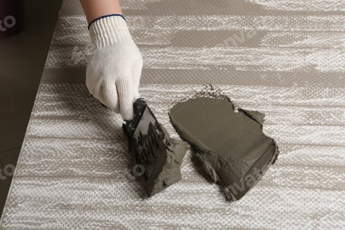 Preview: Worker spreading concrete on ceramic tile with spatula, closeup. Space for text