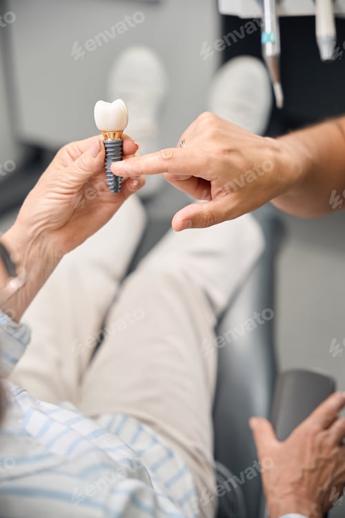 Preview: Female holds model of dental implant in hands