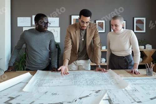 Preview: One of three coworkers making presentation of large sketch on blueprint