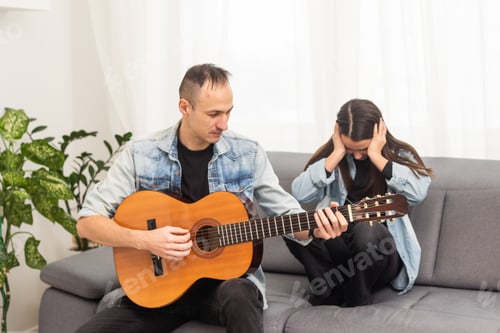 Preview: A father teaching his daughter how to play guitar.