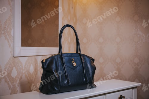Preview: Fashionable black leather bag with a lock on it on the table in the room