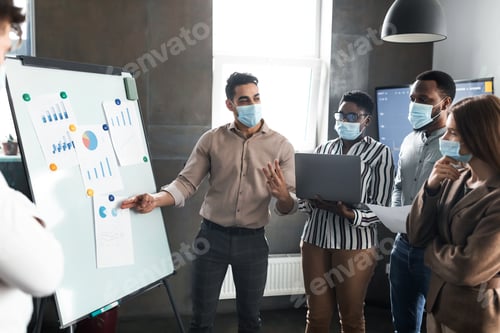 Preview: Employee in protective face mask presenting business strategy on whiteboard