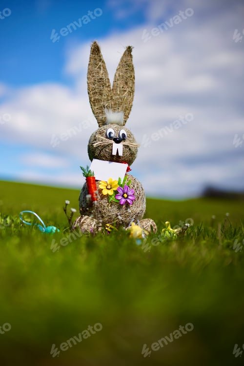 Preview: Vertical shot of a thatched rabbit toy with flowers in a field for Easter