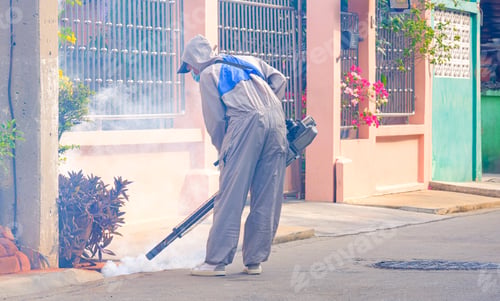 Preview: Healthcare worker spraying insecticide in drainage ditch on the street in residential district area