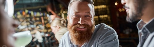 Preview: portrait of cheerful bearded man spending after work time with multicultural friends in bar, banner