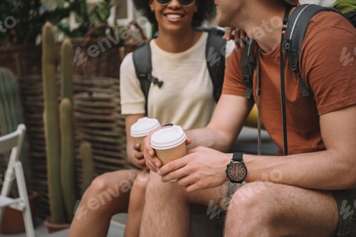Preview: cropped image of couple sitting with disposable cups of coffee