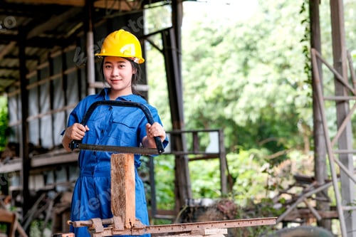 Preview: Asian technician girl is working with hacksaw in the workplace.