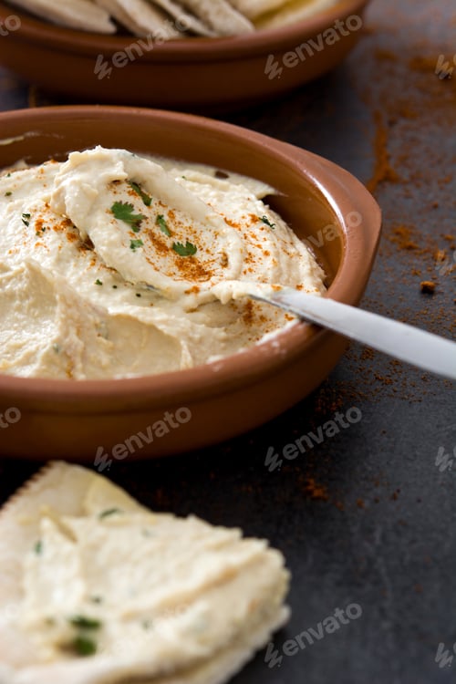 Preview: Creamy hummus garnished with paprika and parsley in terracotta bowl