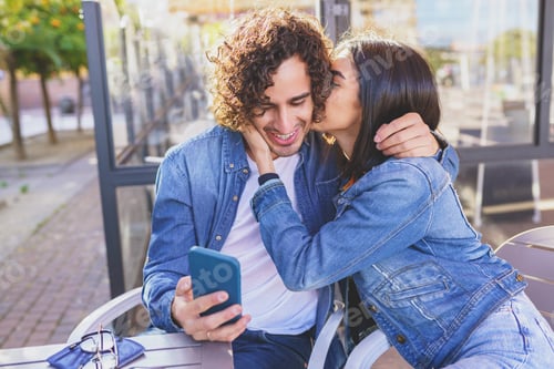 Preview: Arab couple looking at pictures taken with their smartphone outdoors