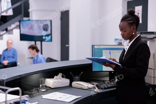 Preview: Receptionist in black suit holding clipboard checking medical expertise and managing patient records