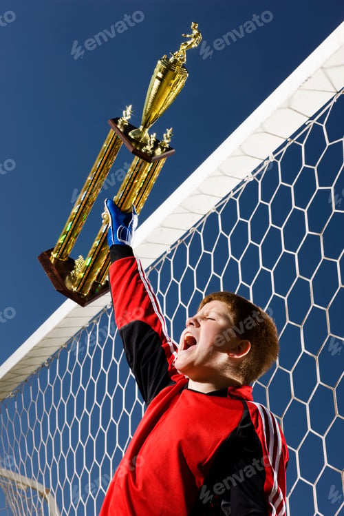 Preview: A goal keeper, a boy in soccer team kit holding up a trophy.