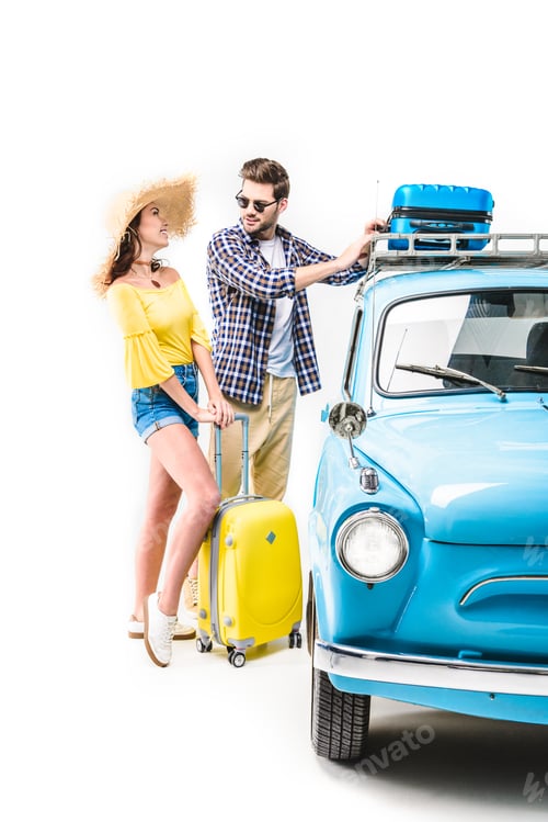 Preview: cheerful young couple of travelers putting luggage on car roof isolated on white