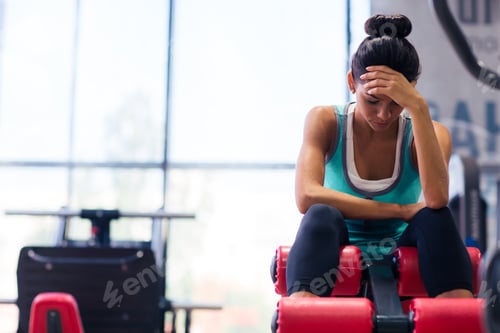 Preview: Tired woman sitting on exercises machine