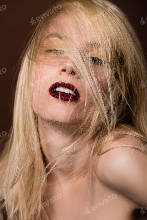 Preview: portrait of seductive naked blonde woman looking at camera on brown