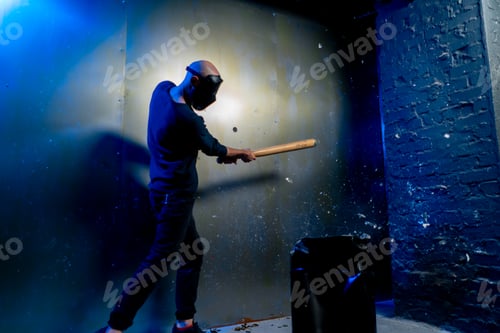 Preview: A man in a protective mask smashes a glass bottle with a bat in a crash room for stress relief