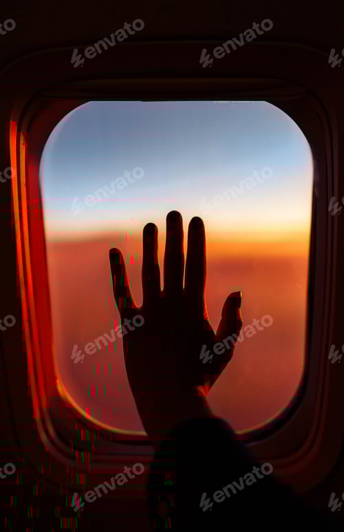 Preview: Mens hand on the porthole in a plane during the flight. Flying above the clouds. Vacation and travel