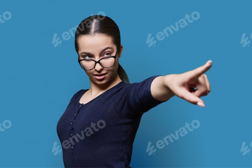 Preview: Serious teenage girl student pointing with finger at space for text