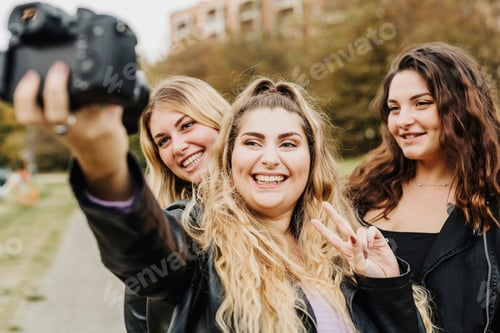Preview: Three friends snapping a happy group selfie outdoors.