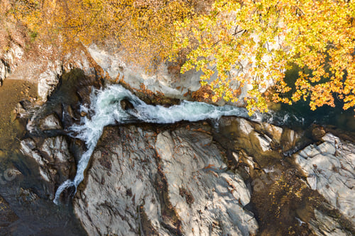 Preview: Top down aerial view of small mountain stream with fast moving clear water between rocky stones in