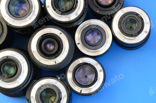 Preview: Several photographic lenses lie on a bright blue background. Space for text