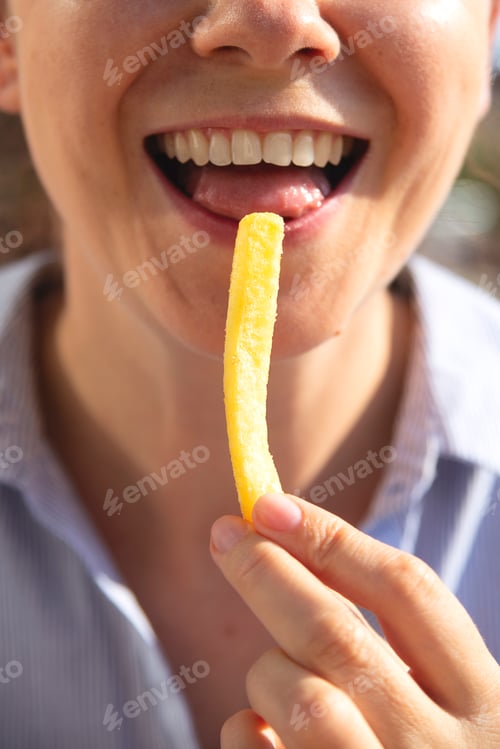 Preview: Woman is eating french fries and smiling.