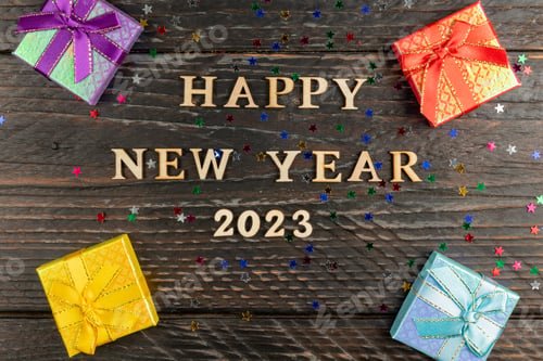 Preview: Multicolored gift box with tied bows. New year presents on wooden table. Text Happy new year 2023.