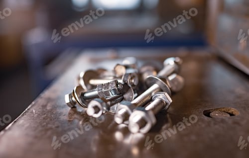 Preview: Metal chrome bolts and nuts lie on the shiny metal surface of the machine