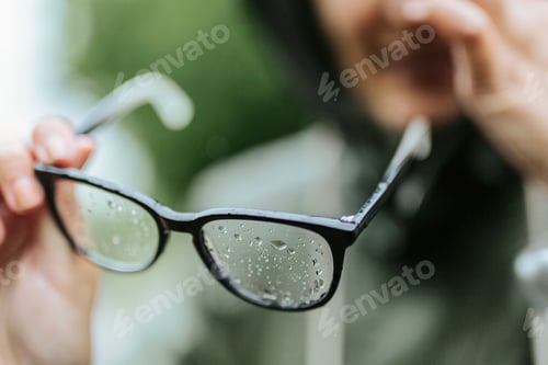 Preview: Close-up of woman holding eyeglasses in rain